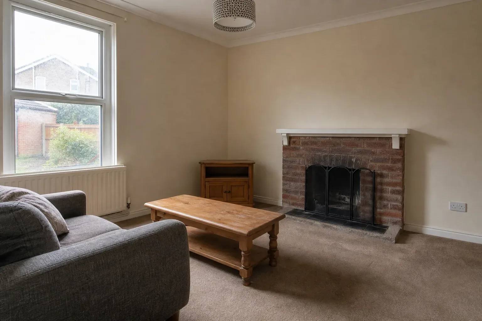 Living room with a plain sofa and fireplace photographed from a corner in daylight