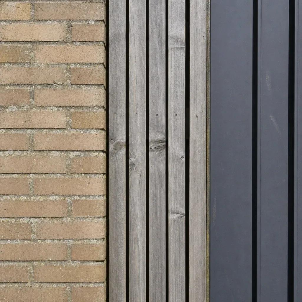 Close view where brick, vertical timber boarding and standing-seam metal meet on one exterior wall