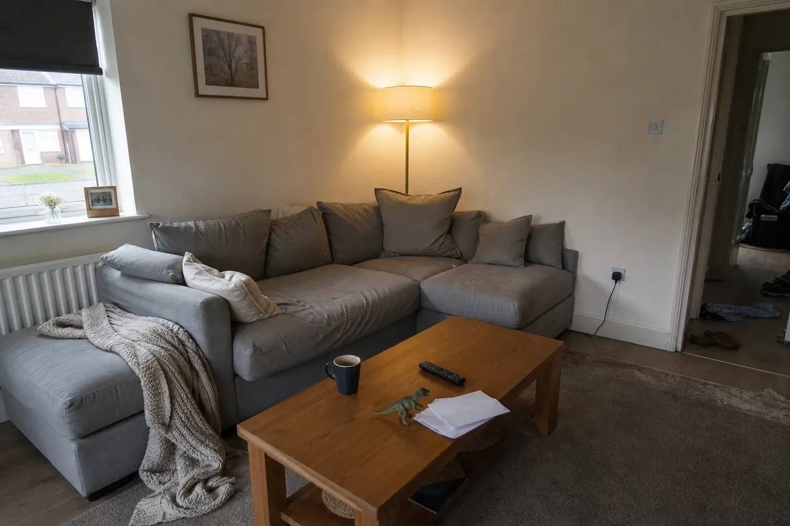 A lived-in family living room with a sectional sofa, scattered toys and opened mail on the coffee table