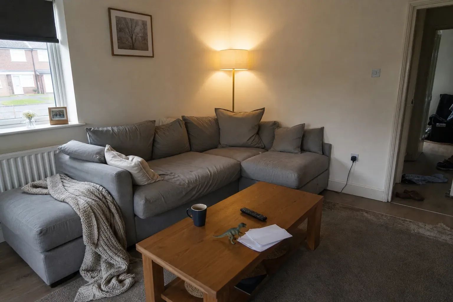 A lived-in family living room with a sectional sofa, scattered toys and opened mail on the coffee table
